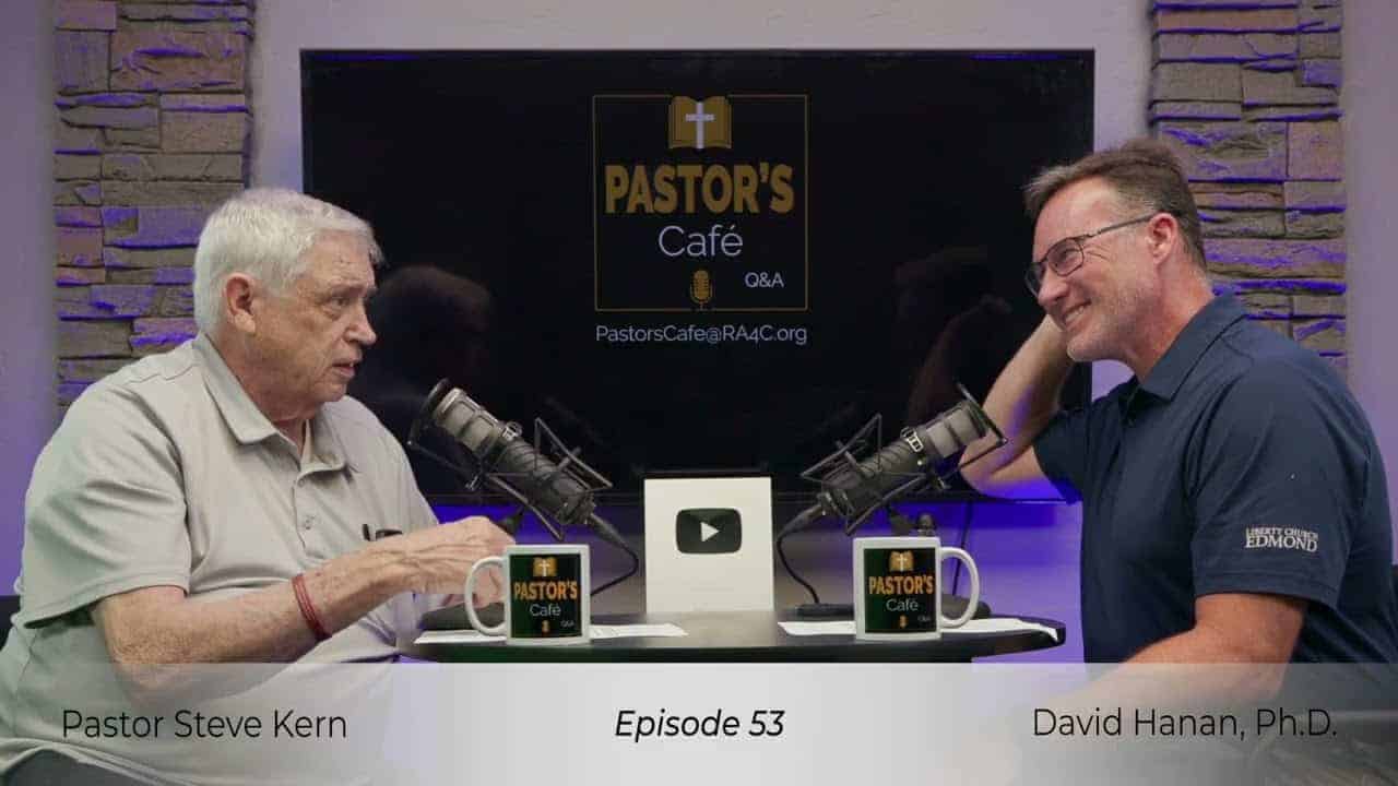 Two pastors engaged in a training session at Liberty Pastors Cafe with microphones and coffee mugs.