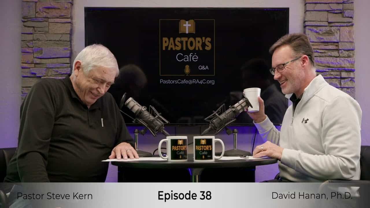 Two pastors engaged in training at Liberty Pastors Cafe with microphones and coffee.