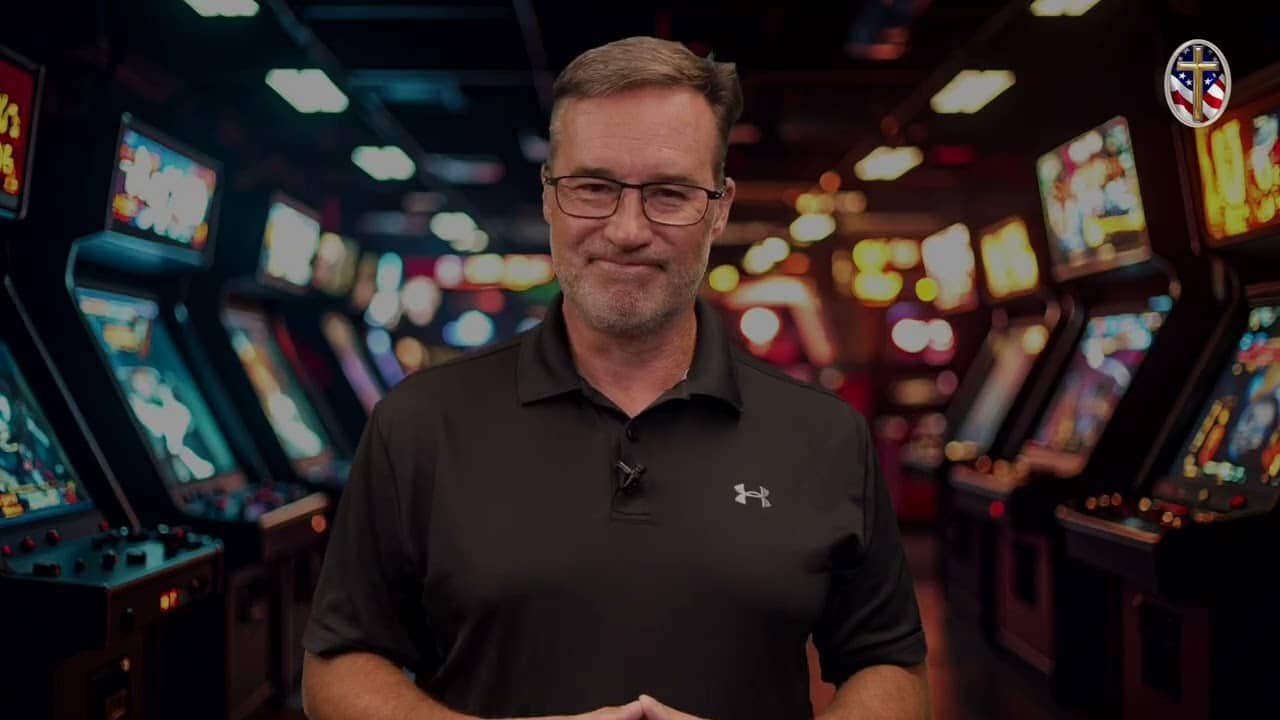 Man in black polo shirt at Liberty Pastors training event with gaming machines in background.